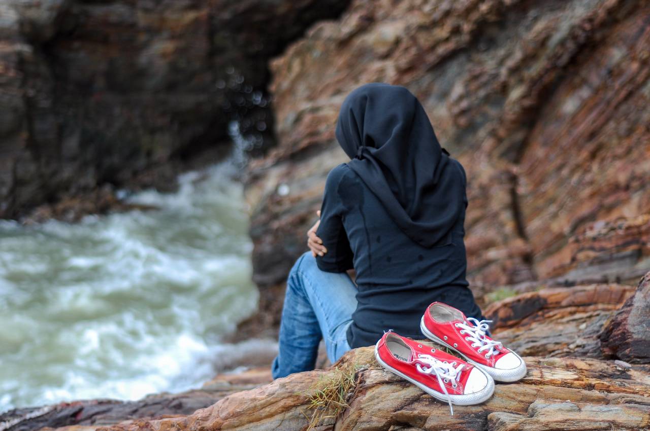 Ragazza da sola in riva al fiume senza scarpe